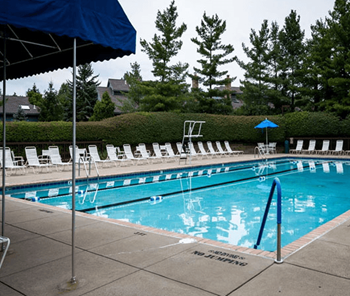 A swimming pool with white chairs and a blue umbrella